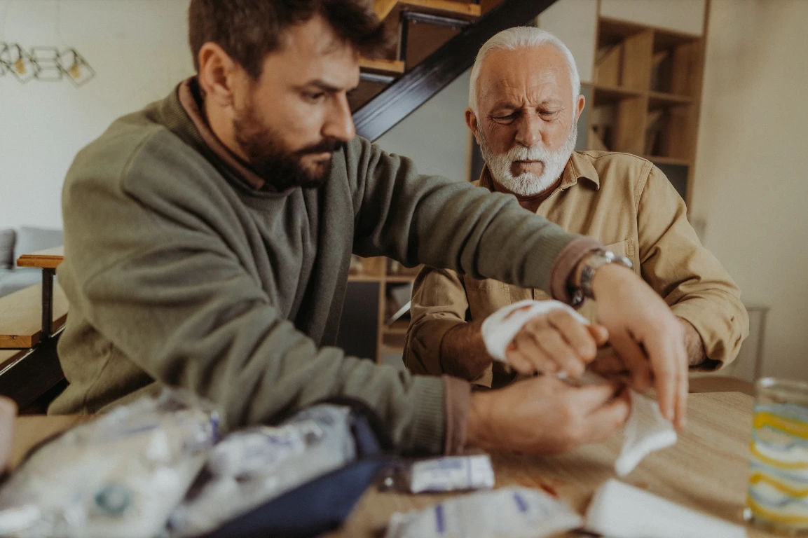 Carer helping senior man bandage myself up. 